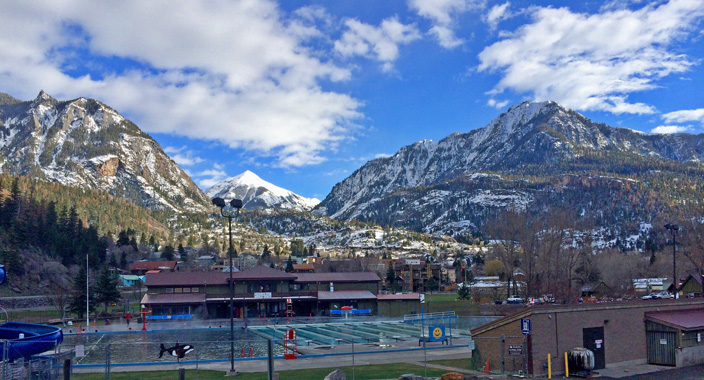 Snow melting on the mountains in early spring behind Ouray Hot Springs Pool in Ouray City, Colorado.